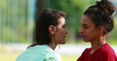 Two young women hugging each other outdoors. Empathic loving hug embrace