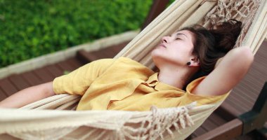 Young woman relaxing lying on hammock