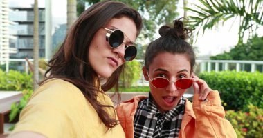 Young women holding camera taking selfie outdoors
