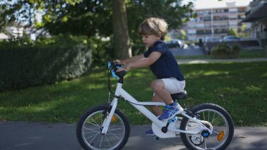 Dışarıda bisiklet süren aktif küçük çocuk bisiklet sürüyor.
