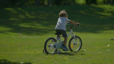 Aktif çocuk parkta bisiklet sürmeyi öğreniyor.