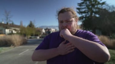 One young fat man having chest pain. Overweight person with panic attack feeling heart pain standing outdoors