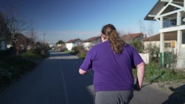 Back of one overweight man running outside in street. A fat person getting back into shape. Motivational concept