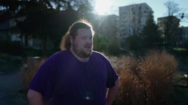 One chubby man taking a deep breath wtih vapor steam in the cold weather outdoors. Overweight person standing outdoors takes a break from walk
