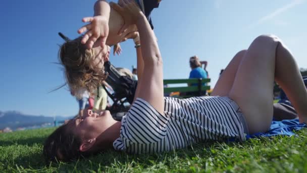Happy Mother Holding Toddler Son Air Laying Outdoors Grass Sunny — Vídeo de Stock