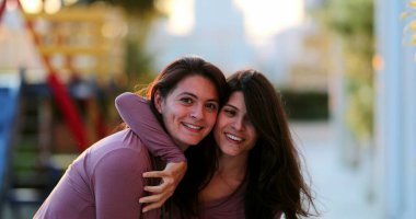 İki yetişkin mutlu kız kardeş, ikiz kardeşlerin dışında aynı kıyafetle poz veriyorlar.