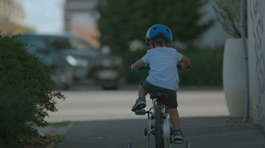 Bisiklete binen çocuğun arkası Sokakta bisiklet süren küçük çocuk kaldırımda bisiklet sürüyor