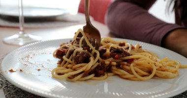 Spagetti makarnası tabakta yakın çatal makarnaya dönüşüyor.