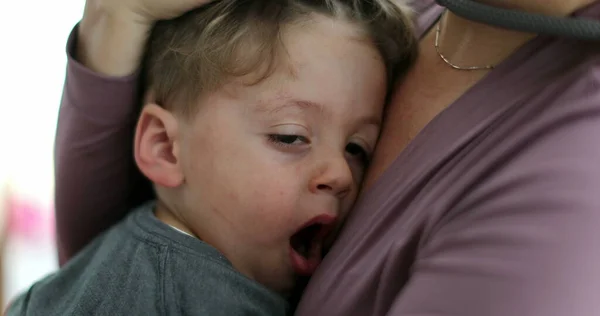 Sleepy child on mother lap mom caresses yawning tired little boy