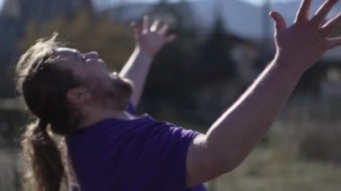One happy young man raising arms in the air celebrating success. Delighted reaction of a person feeling ecstatic standing outdoors. Triumph victory concept