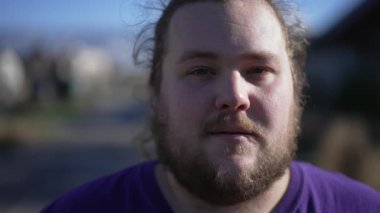 Portrait of a positive chubby young man close up face looking at camera. Casual male caucasian person with beard