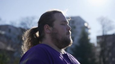 One meditative overweight young man in contemplation outside. Close up face of a relaxed person with eyes closed in meditation