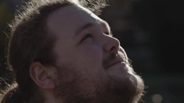 Hopeful young man close up face looking at sky with FAITH. Contemplative serene expression. Tracking shot