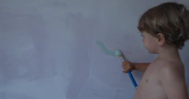 Child painting wall with paint brush. One little mischievous kid paints apartment wall