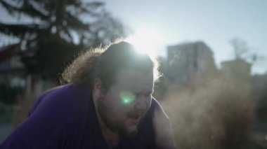 An overweight man takes a break from run with vapor breath during cold day. A fat person getting back to shape recovering from exercising