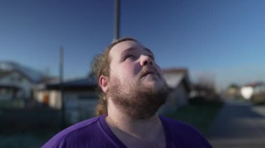 One overweight young man standing outside looking at sky with HOPE and FAITH. Hopeful person close up face