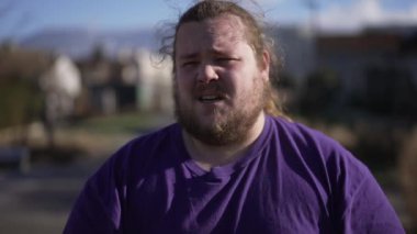 One anxious young man standing outdoors feeling distressed. An unhappy overweight guy suffering from mental regret