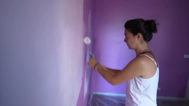 用白色粉刷紫色墙壁的人 正在整修房屋的妇女在粉刷新家 女性画家 — 图库视频影像
