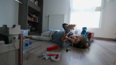 Yatak odasında yerde tek başına oynayan küçük bir çocuk. Küçük çocuk evde yerde yatıyor.