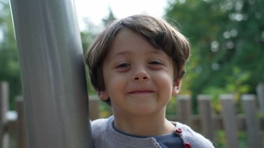 Neşeli mutlu çocuk dışarıda gülümseyen yüzü kapat. Küçük bir çocuk parkta mutlu bir şekilde duruyor.