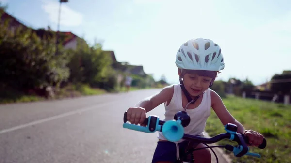 Happy cyclist kid rides bike outdoors road bicycle lane. Smiling sportive child protective helmet cycling in summer warm day