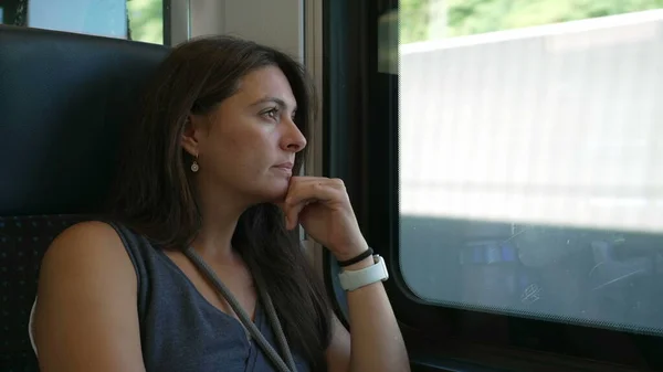 Woman sitting by train window traveling by high speed railroad transportation