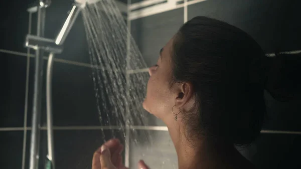 Woman washing face inside shower bath. Female person daily hygiene routine