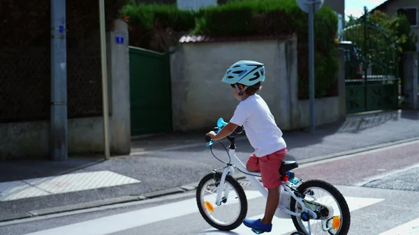 Child crossing street with bicycle and helmet. Sportive kid riding bike with wheels in city street crosswalk