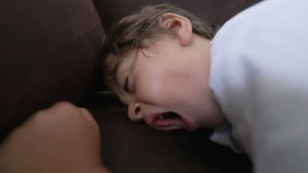 One small boy sleeping on couch. Tired Child close up face yawning falls asleep