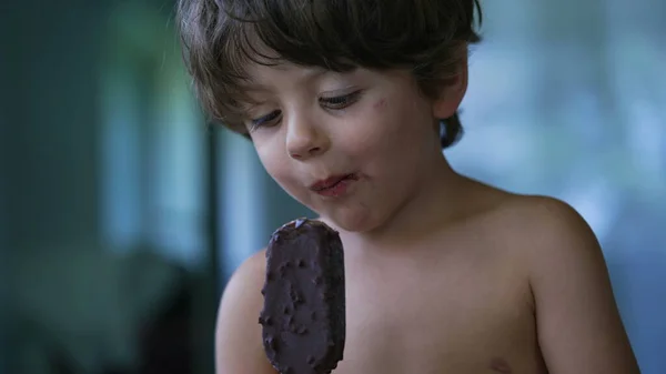 Young boy taking a bite of ice cream. Small child eats unhealthy dessert. Kid eating chocolate icecream sweet