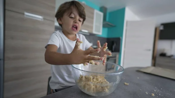 Cute child with messy hands while preparing dough. Kid cooking food dirty hand