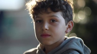 Portrait of a young boy close up face looking at camera with serious expression. One handsome preteen kid