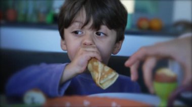 One cute little boy eating pancake for breakfast in the morning. Child closeup face eats food