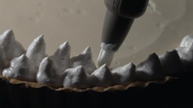 Pastry bag adding cream on top of cake decoration. Preparing sweet dessert