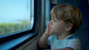 Trenin camına yaslanmış küçük bir çocuk manzarayı seyrediyor. Bir çocuk taşınıyor.