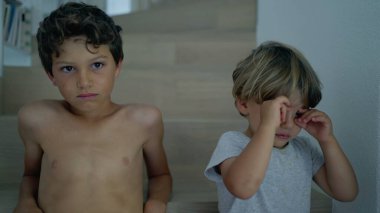 Oyuncu küçük kardeş büyük kardeşle takılıyor. Sevimli samimi, özgün bir aile anı. Çocuklar gülümseyerek eğleniyor. Mutluluk kavramı