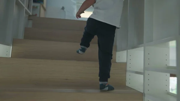 Child going up the staircases at home. One little boy climbing stairs going to the second floor of house