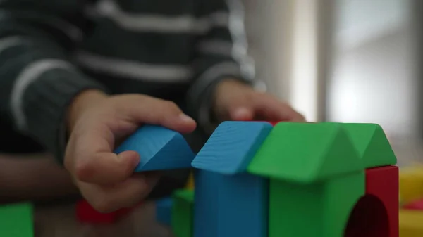 Kid hand plays with colorful blocks. Child playing with building block construction. Child making house with blocks. Childhood creative development concept