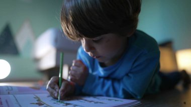 Kırmızı kalemle kağıda resim çizen odaklı küçük bir çocuk. Yaratıcı sanatsal faaliyet gösteren yakın çekim çocuk yüzü