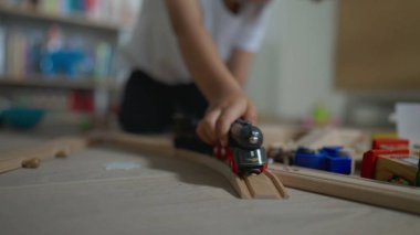 Çocuk odada oynuyor. Küçük bir çocuk tek başına oyuncaklarla oynuyor. Küçük çocuk yatak odasında demiryolu döşemesiyle