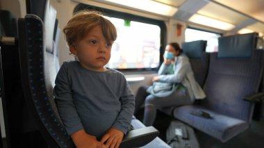 Trenle seyahat eden küçük çocuk ifadesiz sıkılmış bir çocuk.