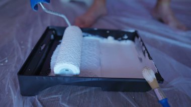 Ev tadilatı yaparken el kamerasında boya silindiri var. Duvarı beyaz renge boyayan kadın