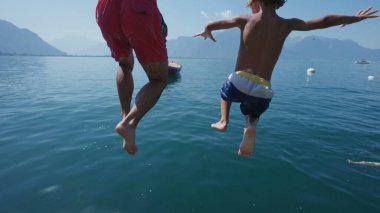 Baba ve çocuk iskelede koşuyor ve göl suyuna atlıyorlar.