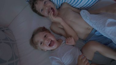 Yorganın altında iki küçük çocuğu açığa çıkarmak. Sabah yatağında mutlu çocuklar uyanıyor. Otantik gerçek hayat güler ve gülümser
