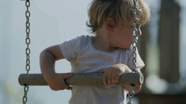 Küçük bir çocuk oyun parkındaki merdivene tırmanıyor. Dışarıda oynayan aktif bir çocuk. Çocukluk gelişimi kavramı. Çocuk dışarıda eğleniyor.