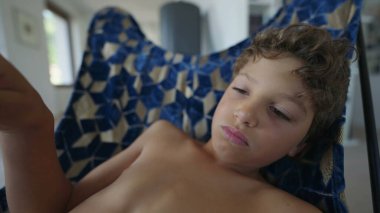 Sad young boy siitting at home with nothing to do. Bored male preteen child. Kid feeling boredom closeup face. Depressed childhood emotion in Vertical Video