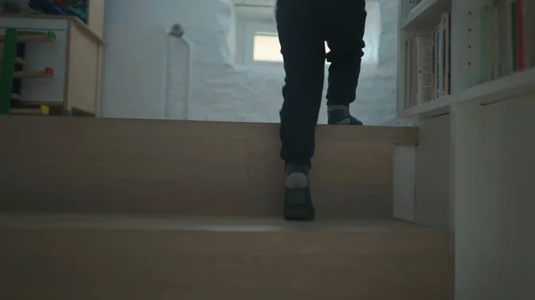 Child feet walking up the stairs. Kid legs climbing staircases at home. Boy going to the second floor of house