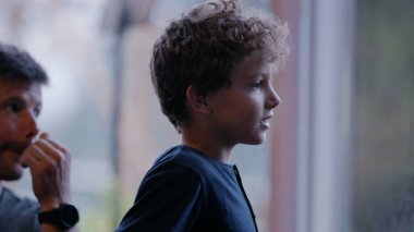 Pencere kenarında dikilip bakan düşünceli bir çocuk