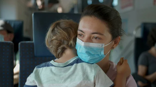 Mother wearing face mask while traveling by train holding child. Person during pandemic