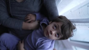 Mother caressing child hair wearing pajamas in the morning. Small boy cuddling with parent. Family love and affection